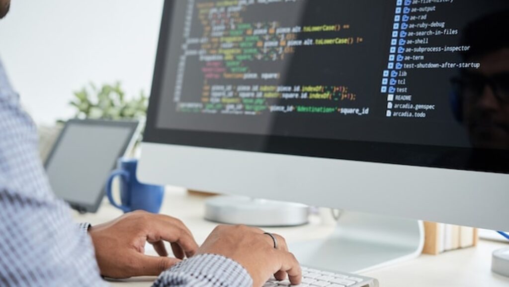 mans hands typing on apple imac